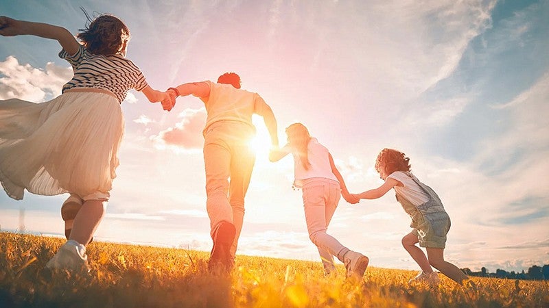 a family holding hands walking towards the sunset