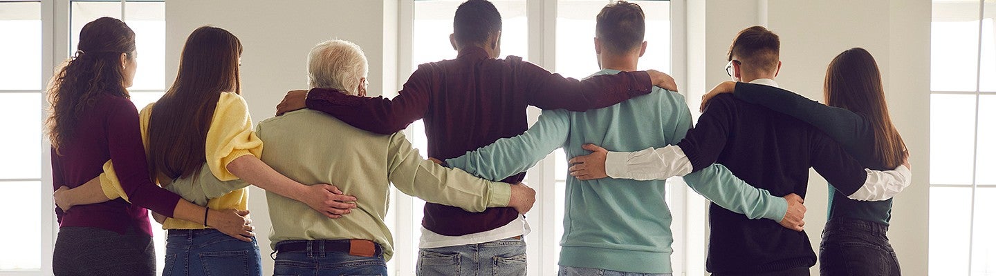 group of adult individuals standing inline with arms around each other